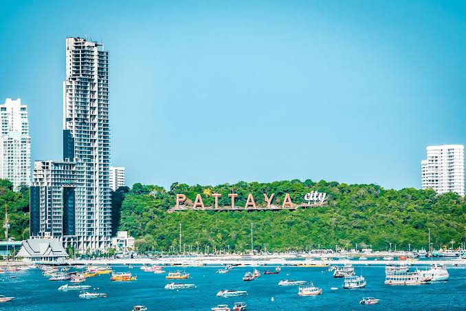 Pattaya City hillside sign over the bay with the Pratumnak skyline and tourist boats in the foreground