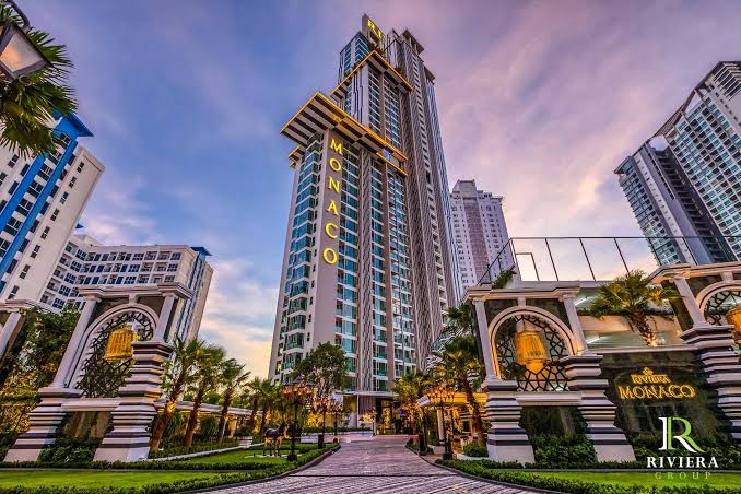 Riviera Monaco Pattaya entrance with illuminated tower and landscaped boulevard at dusk